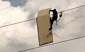 Man takes the signboard stuck on high-stressed wire in Noida